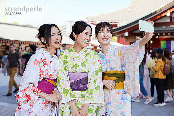 Japanese friends wearing yukata visiting traditional temple in Tokyo