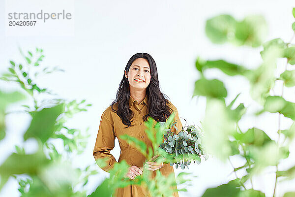 Japanese woman in a brown dress standing in front of plants