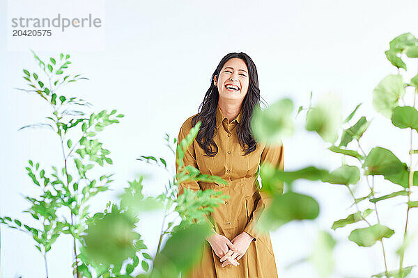 Japanese woman in a brown dress standing in front of plants