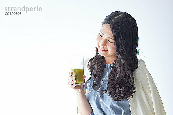 Japanese woman holding a glass of green juice