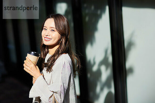 Japanese woman holding coffee cup and smiling