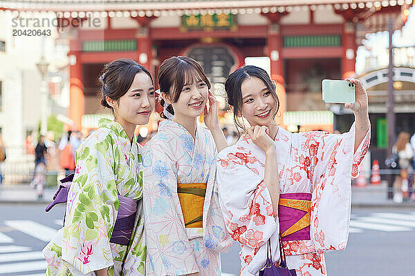 Japanese friends wearing yukata visiting traditional temple in Tokyo