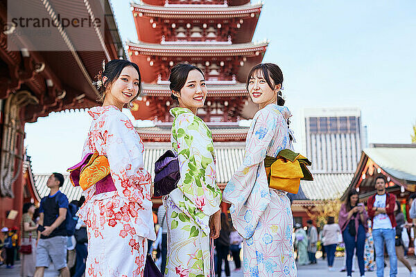 Japanese friends wearing yukata visiting traditional temple in Tokyo