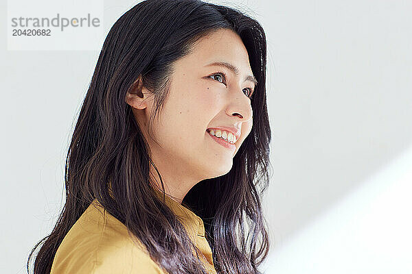 Japanese woman in a brown dress standing in front of a white wall