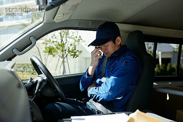 Japanese delivery man sitting in the driver seat