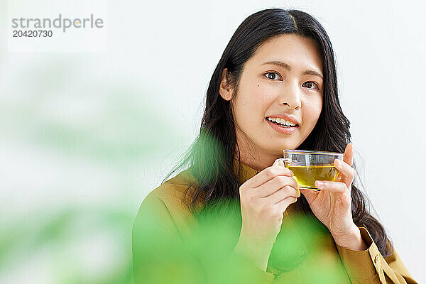 Japanese woman drinking tea against white background