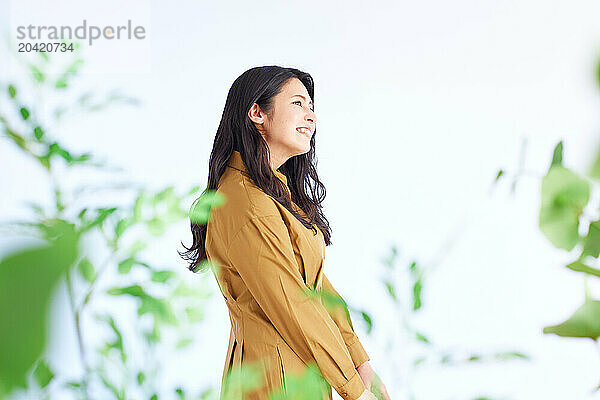 Japanese woman in a brown dress standing in front of plants