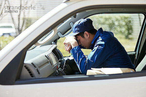 Japanese delivery man sitting in the driver seat