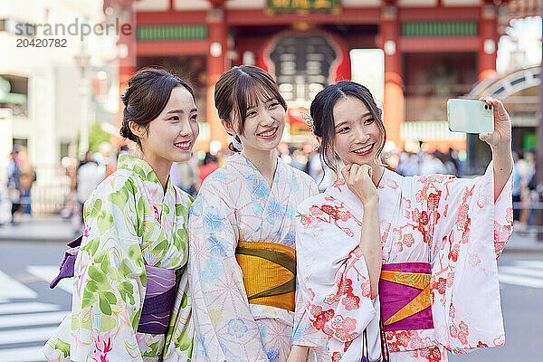 Japanese friends wearing yukata visiting traditional temple in Tokyo