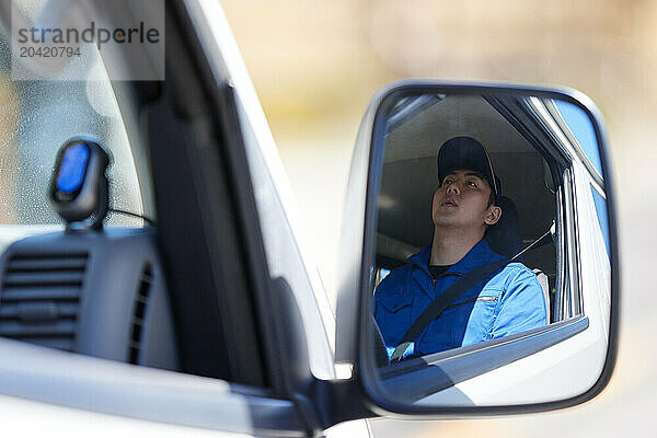 Japanese delivery man sitting in the driver seat