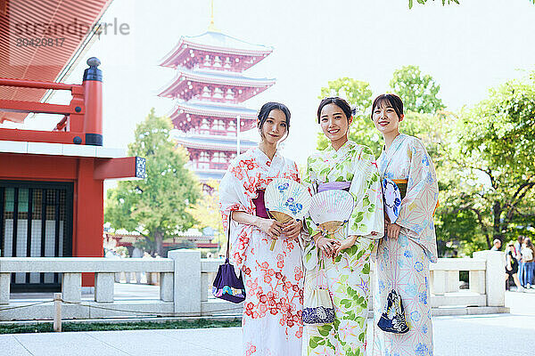 Japanese friends wearing yukata visiting traditional temple in Tokyo