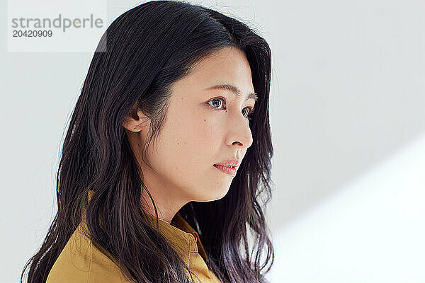 Japanese woman in a brown dress standing in front of a white wall