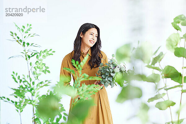 Japanese woman in a brown dress standing in front of plants