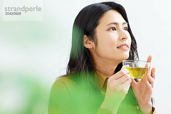 Japanese woman drinking tea against white background