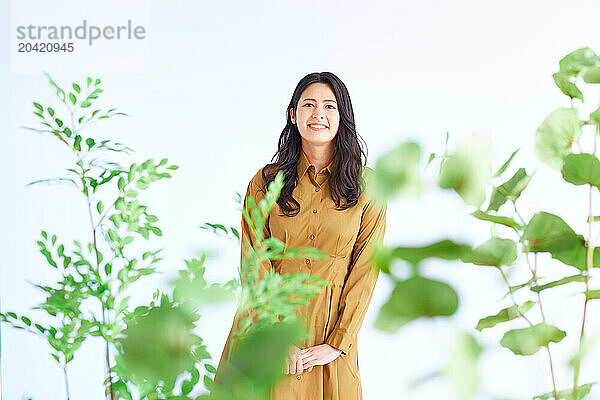 Japanese woman in a brown dress standing in front of plants