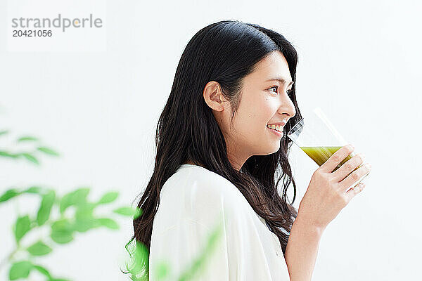 Japanese woman holding a glass of green juice