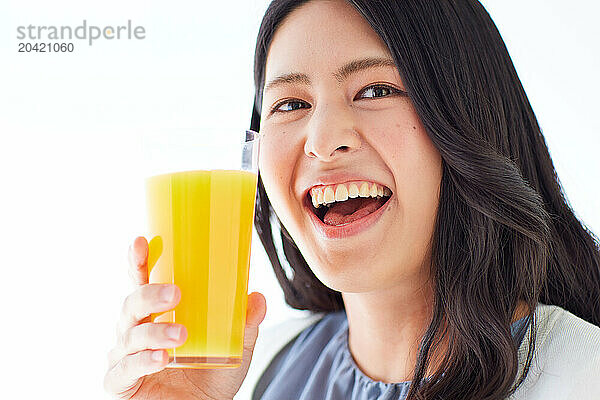 Japanese woman holding a glass of orange juice