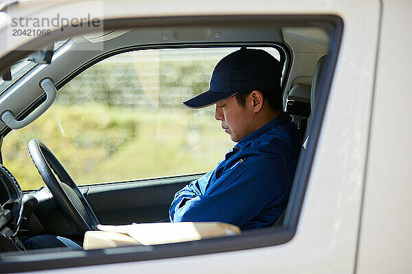 Japanese delivery man sitting in the driver seat