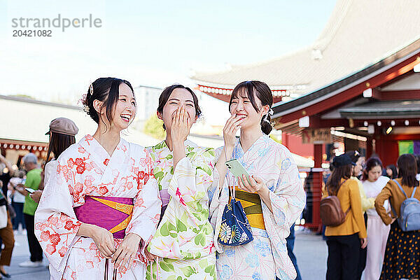 Japanese friends wearing yukata visiting traditional temple in Tokyo