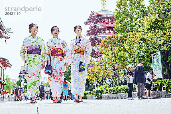 Japanese friends wearing yukata visiting traditional temple in Tokyo