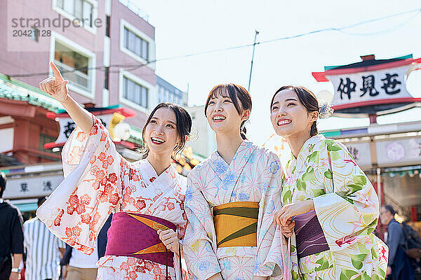 Japanese friends wearing yukata visiting traditional temple in Tokyo