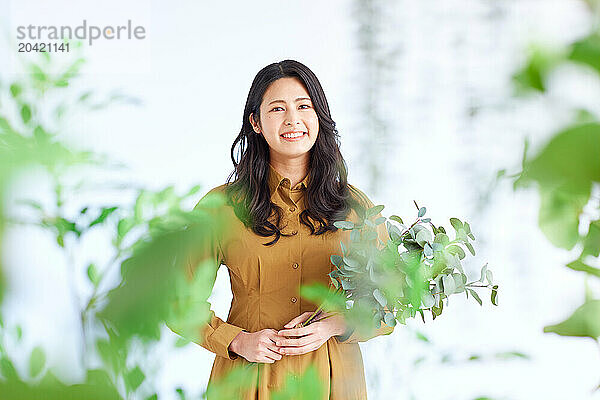 Japanese woman in a brown dress standing in front of plants