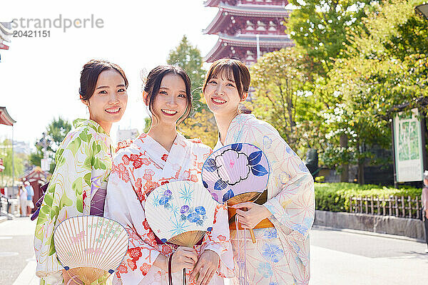 Japanese friends wearing yukata visiting traditional temple in Tokyo