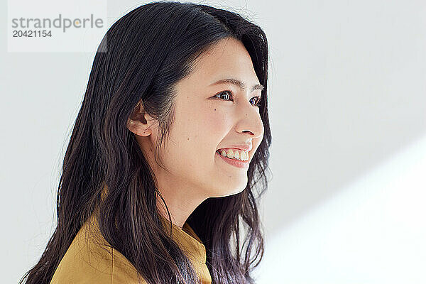 Japanese woman in a brown dress standing in front of a white wall