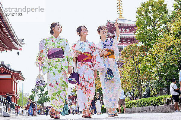 Japanese friends wearing yukata visiting traditional temple in Tokyo