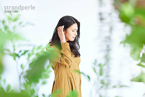 Japanese woman in a brown dress standing in front of plants