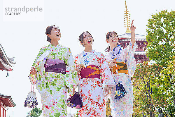 Japanese friends wearing yukata visiting traditional temple in Tokyo