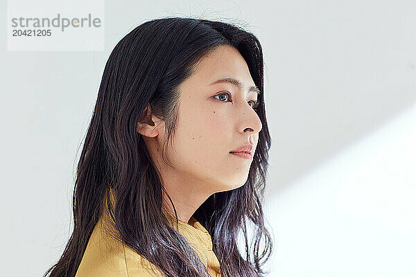 Japanese woman in a brown dress standing in front of a white wall