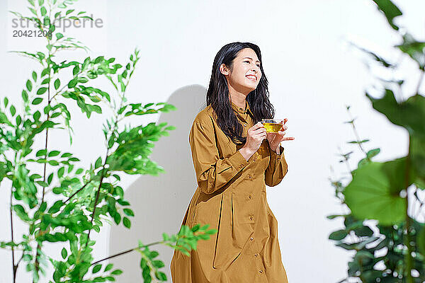 Japanese woman in a brown dress standing in front of plants