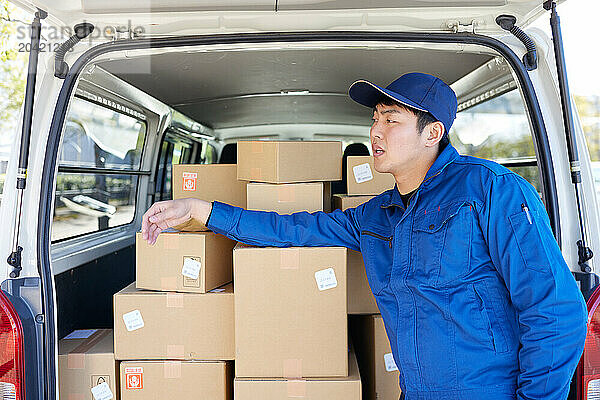 Japanese delivery man checking boxes in the car