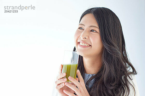 Japanese woman holding a glass of green juice