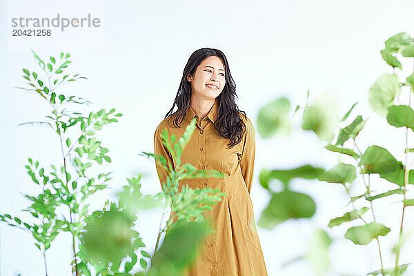 Japanese woman in a brown dress standing in front of plants