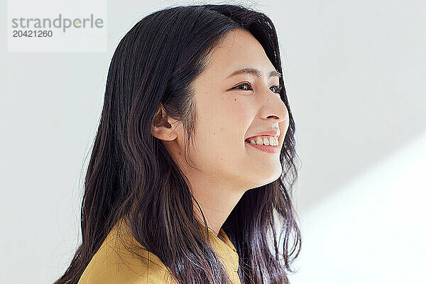 Japanese woman in a brown dress standing in front of a white wall