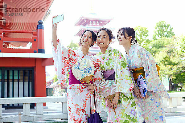 Japanese friends wearing yukata visiting traditional temple in Tokyo