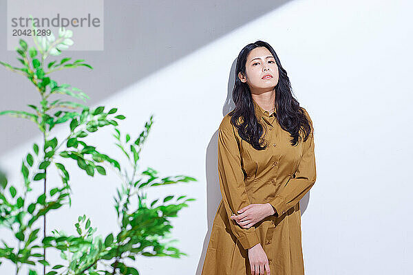 Japanese woman in a brown dress standing in front of plants