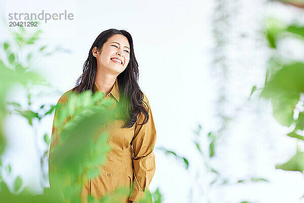 Japanese woman in a brown dress standing in front of plants