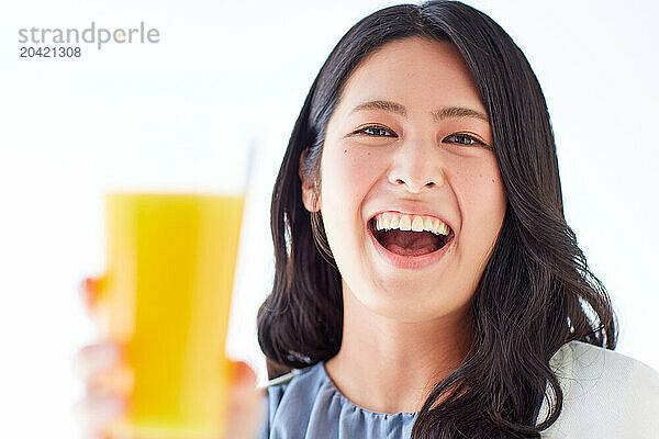 Japanese woman holding a glass of orange juice