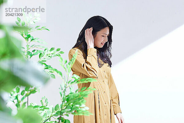 Japanese woman in a brown dress standing in front of plants