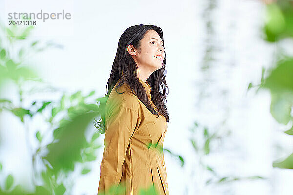 Japanese woman in a brown dress standing in front of plants