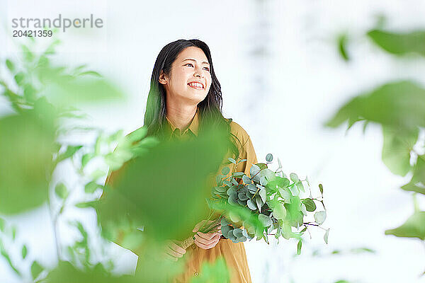 Japanese woman in a brown dress standing in front of plants