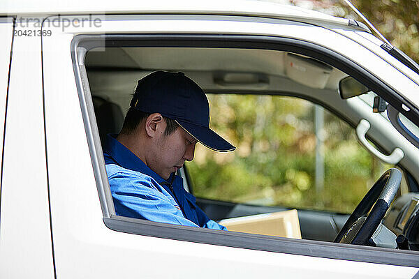 Japanese delivery man sitting in the driver seat