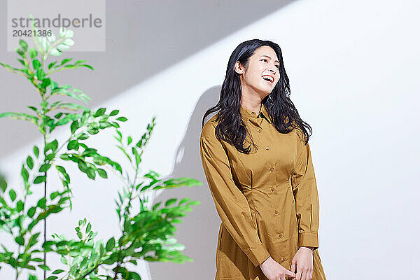 Japanese woman in a brown dress standing in front of plants