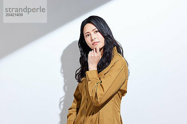 Japanese woman in a brown dress standing in front of a white wall