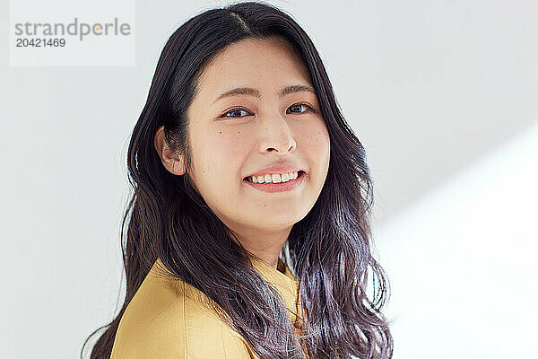 Japanese woman in a brown dress standing in front of a white wall