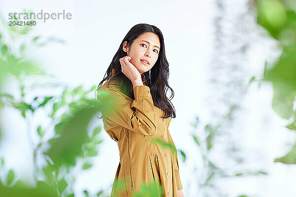 Japanese woman in a brown dress standing in front of plants