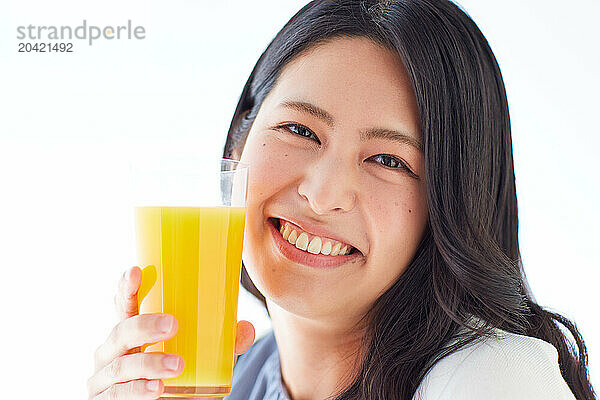 Japanese woman holding a glass of orange juice